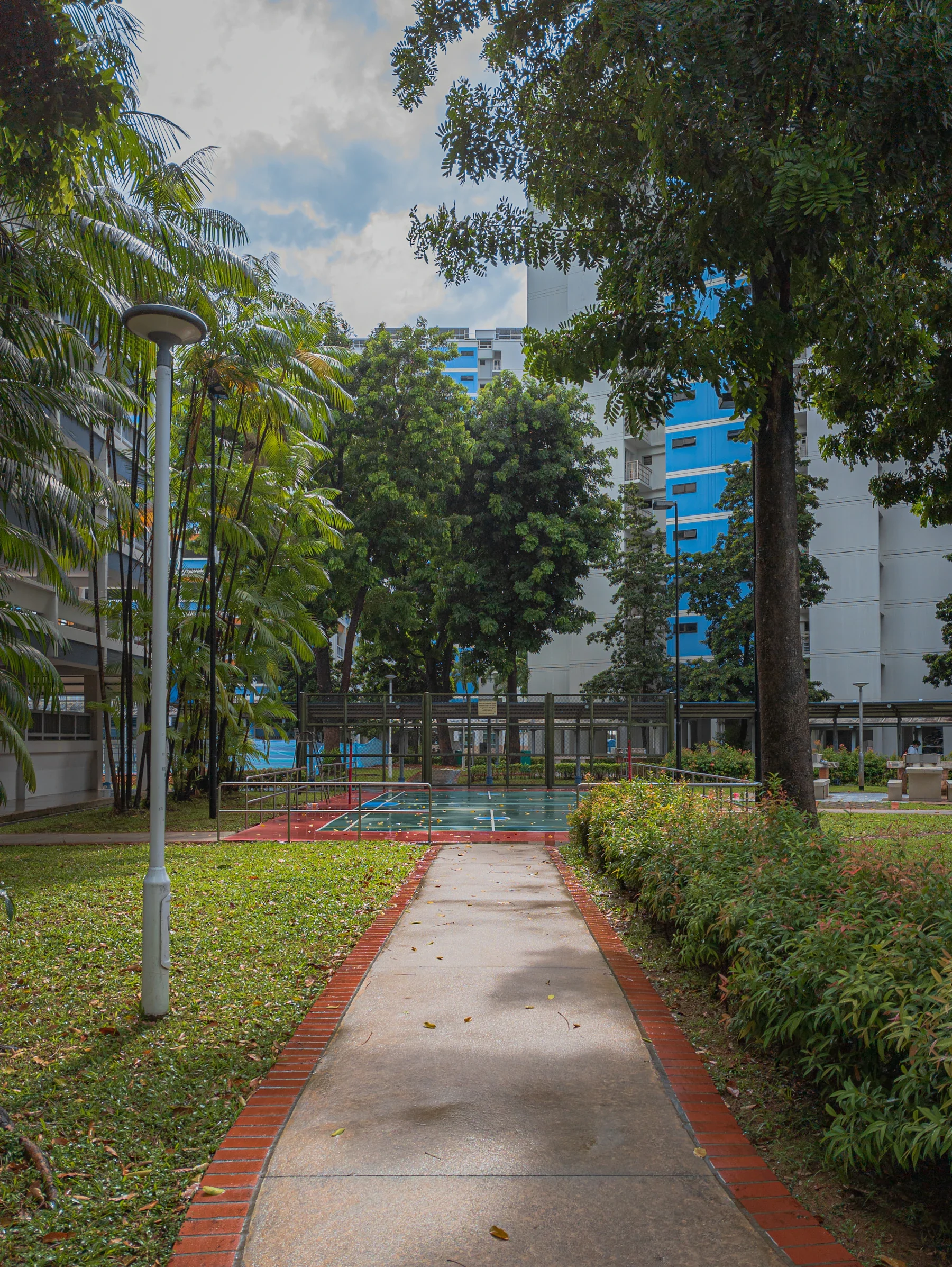 A shaded community walkway among homes and trees in Singapore